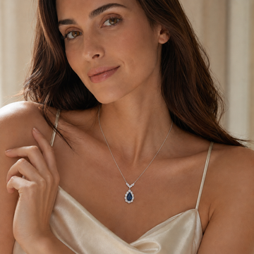 Elegant woman wearing a pear-cut royal blue sapphire pendant necklace
