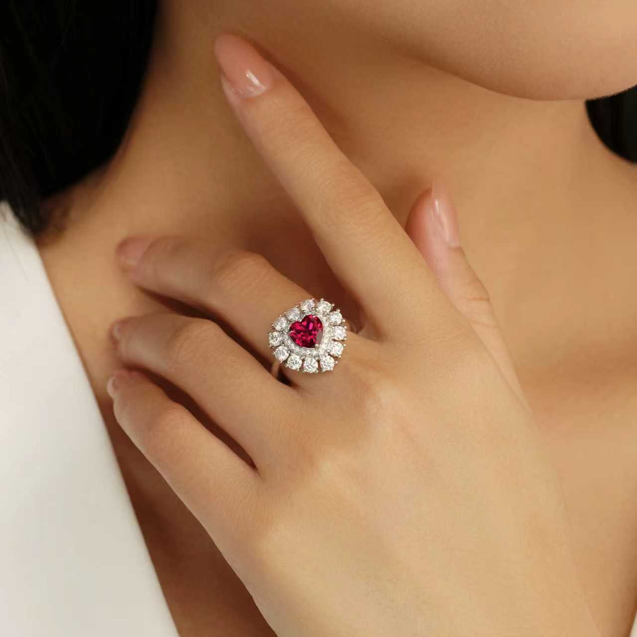 Heart-shaped lab-grown ruby ring worn on hand with moissanite halo in 925 sterling silver