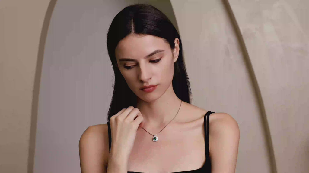 Model wearing the Moon Halo Emerald Necklace with a vivid green lab-grown emerald and moissanite halo pendant