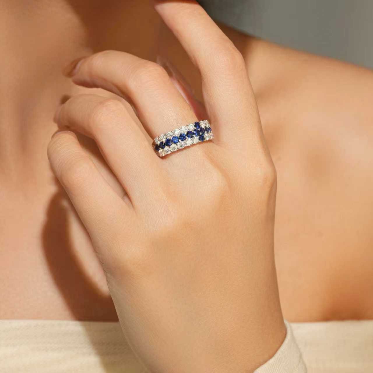 Close-up of cross-inspired lab-grown blue sapphire and moissanite ring worn on hand in rhodium-plated 925 sterling silver