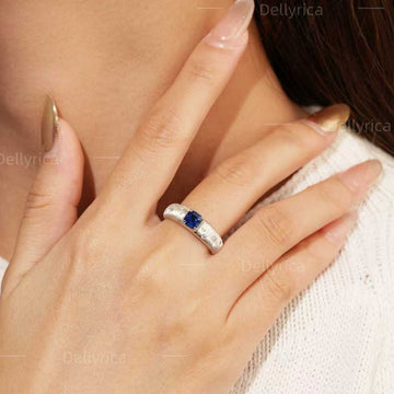 Starburst lab-grown blue sapphire ring with D-color moissanite accents worn on hand in rhodium-plated 925 sterling silver