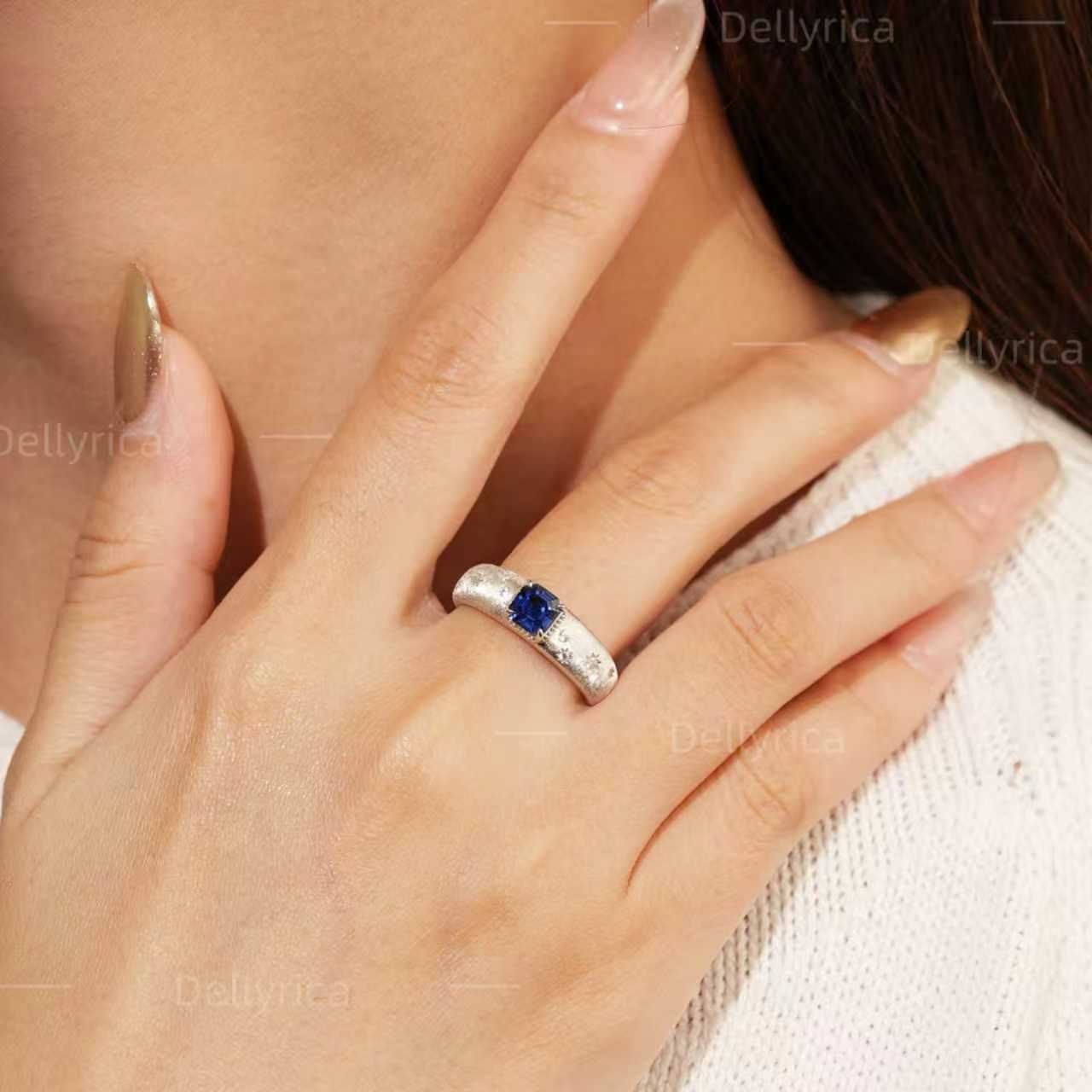 Starburst lab-grown blue sapphire ring with D-color moissanite accents worn on hand in rhodium-plated 925 sterling silver