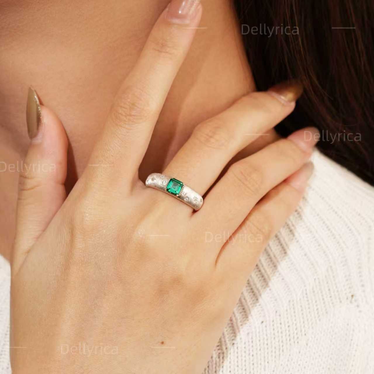 Starburst lab-grown emerald promise ring with D-color moissanite accents worn on hand in rhodium-plated 925 sterling silver